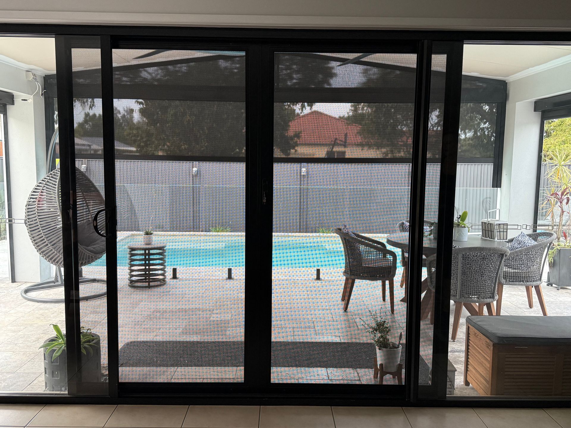 A White Door With A Black Screen Is Open To A Brick Wall — Roo’s Door & Window Maintenance In Sippy Downs, QLD