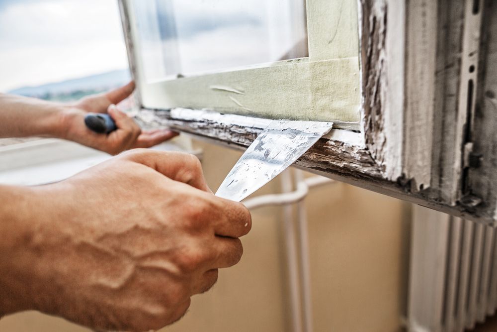 A Person Is Removing Paint From A Window Sill — Roo’s Door & Window Maintenance In Sippy Downs, QLD