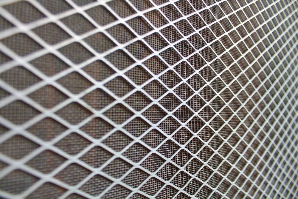 A Close Up Of A Metal Mesh With Holes In It — Roo’s Door & Window Maintenance In Sippy Downs, QLD