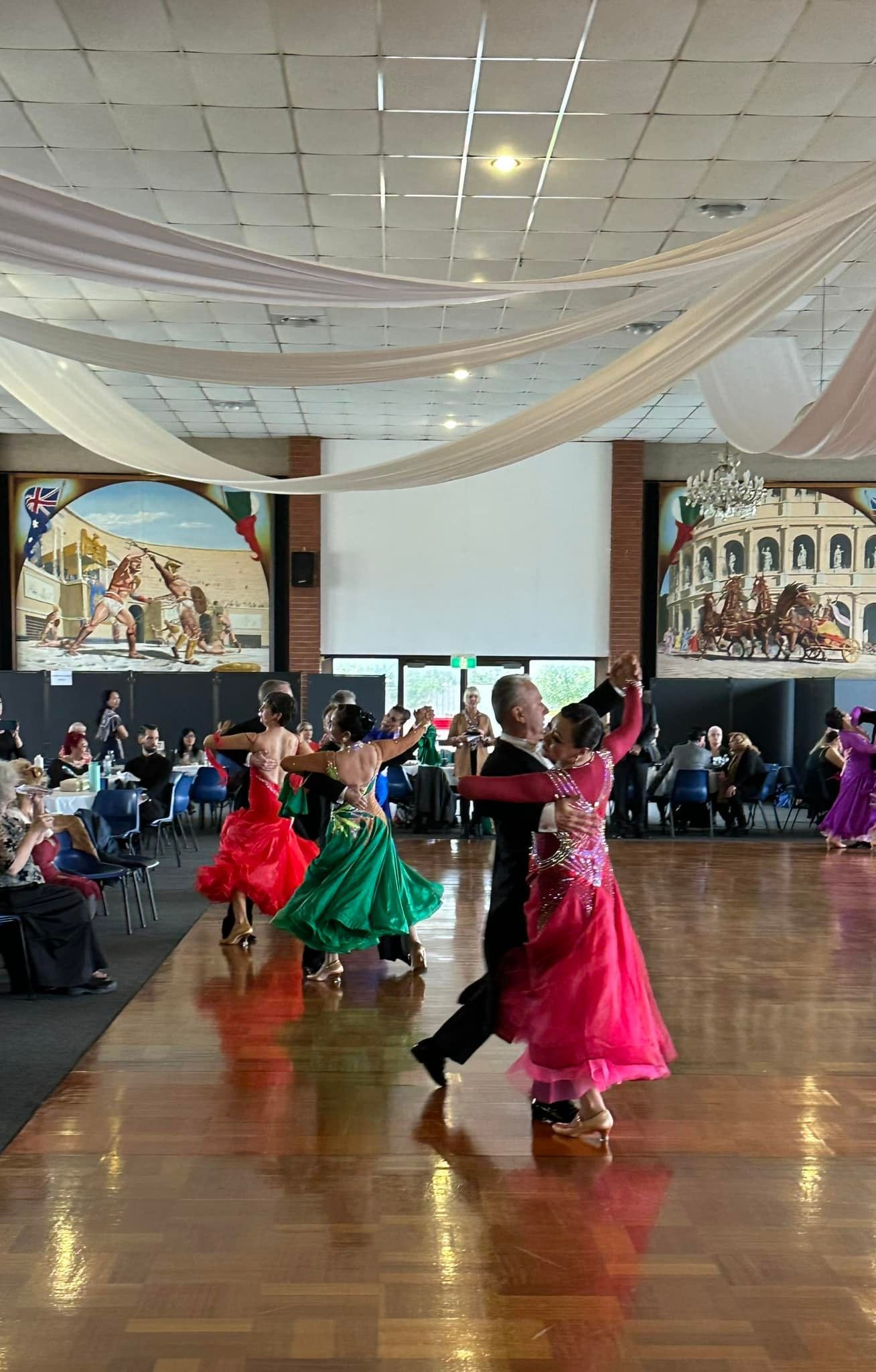 A group of people are dancing on a dance floor in a large room.