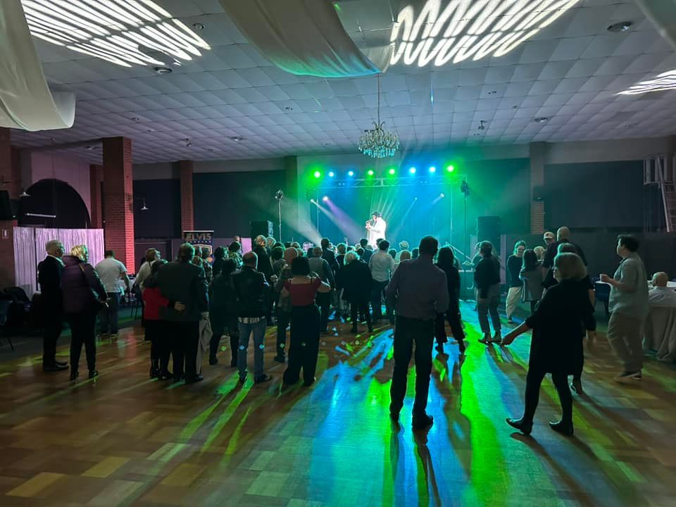 A large group of people are dancing in a large room.