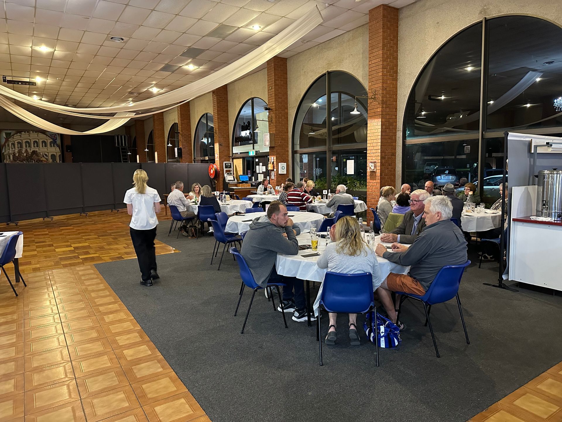 A group of people are sitting at tables in a large room.