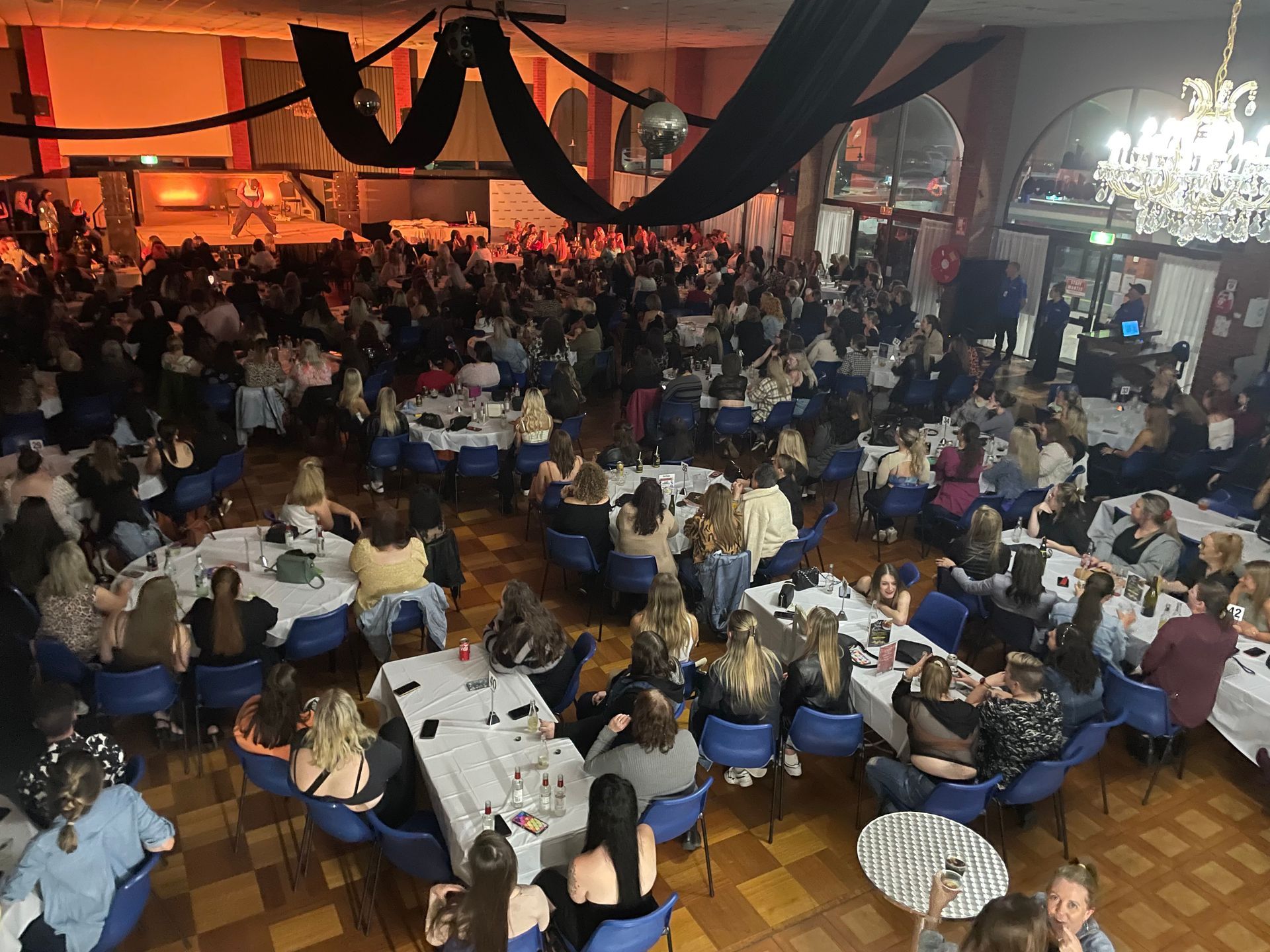 A large group of people are sitting at tables in a large room.