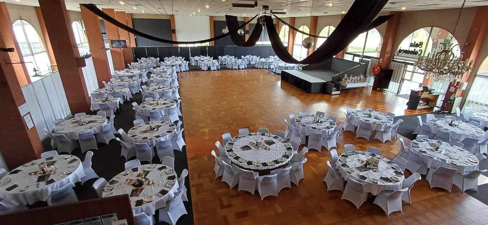 A large room with tables and chairs set up for a wedding reception.