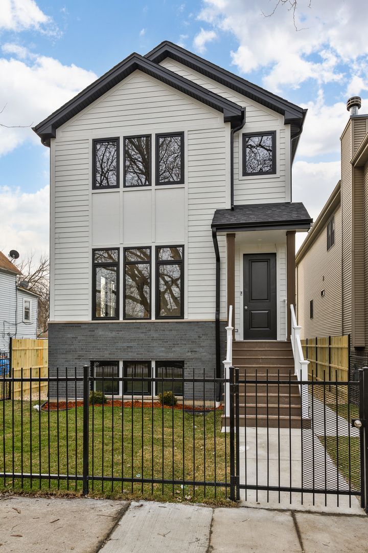 Two-story house with white siding, black trim, and a black front door with steps leading up.
