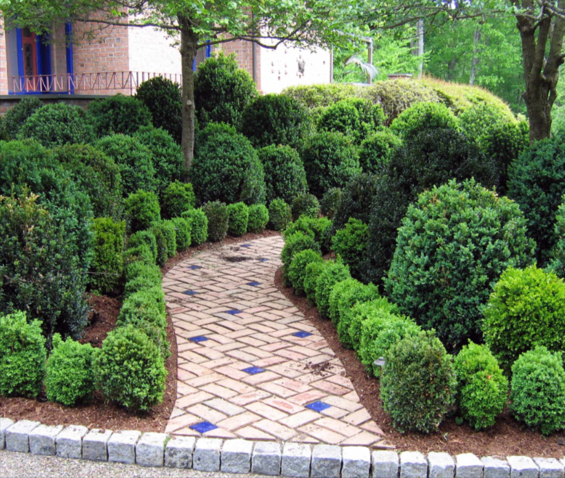 Woman wearing yellow gloves cleaning floor in a living room, smiling. Cleaning supplies in a blue bin.