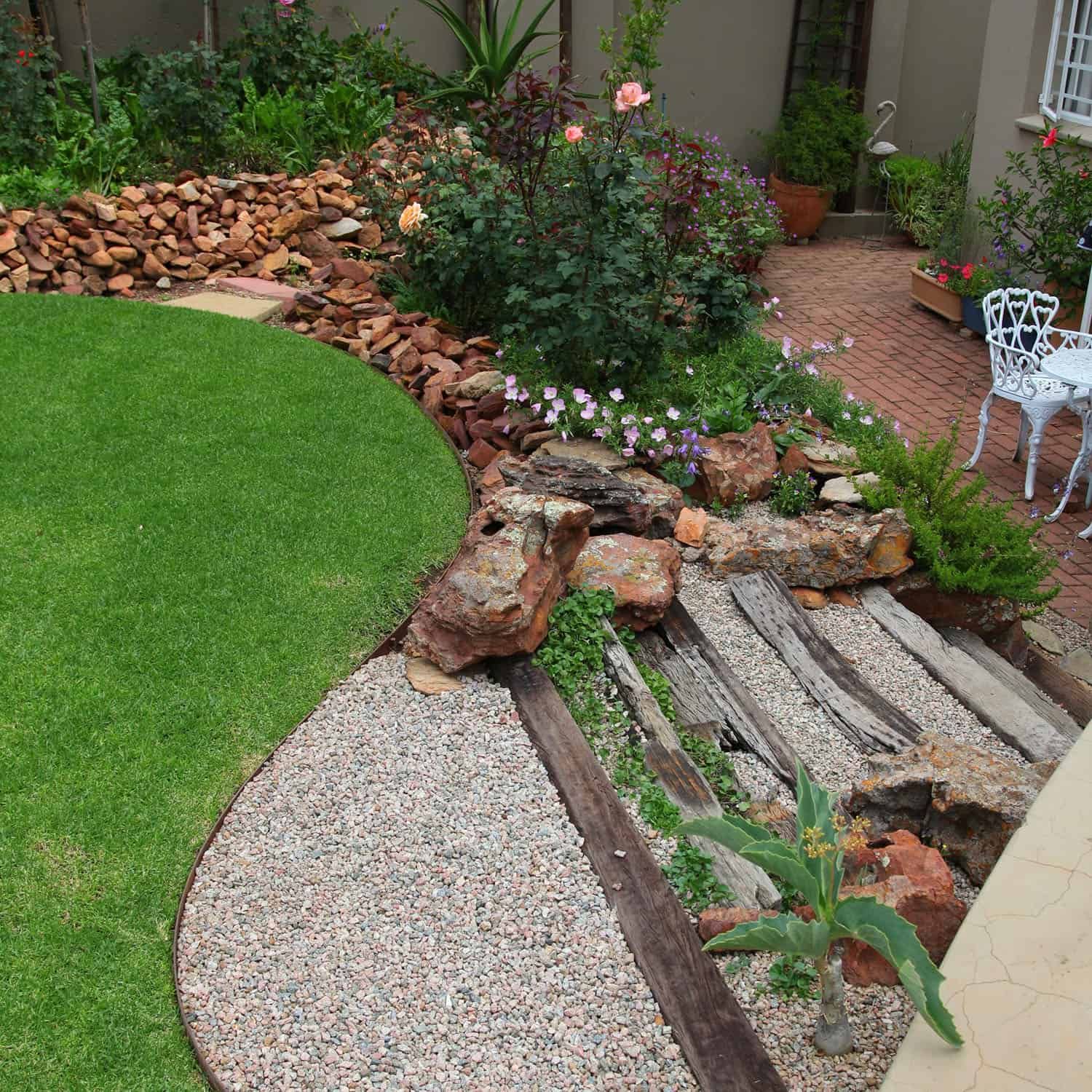 Woman wearing yellow gloves cleaning floor in a living room, smiling. Cleaning supplies in a blue bin.