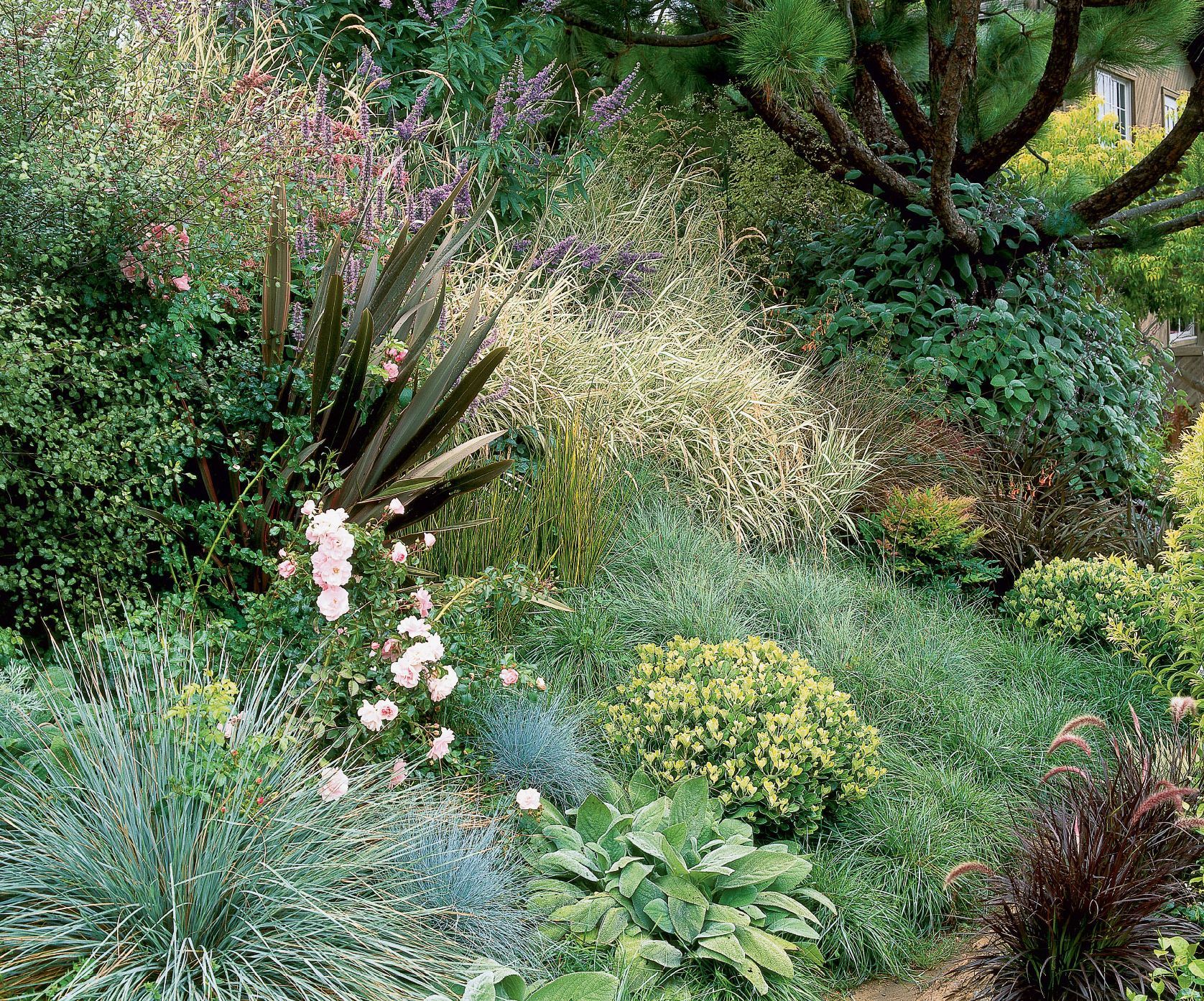 Woman wearing yellow gloves cleaning floor in a living room, smiling. Cleaning supplies in a blue bin.