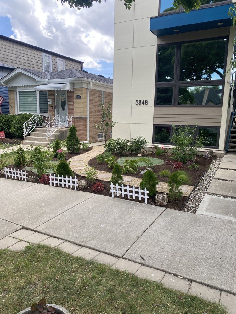 Landscaped front yard with a white picket fence, pathway, and modern house.