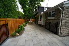 Woman wearing yellow gloves cleaning floor in a living room, smiling. Cleaning supplies in a blue bin.