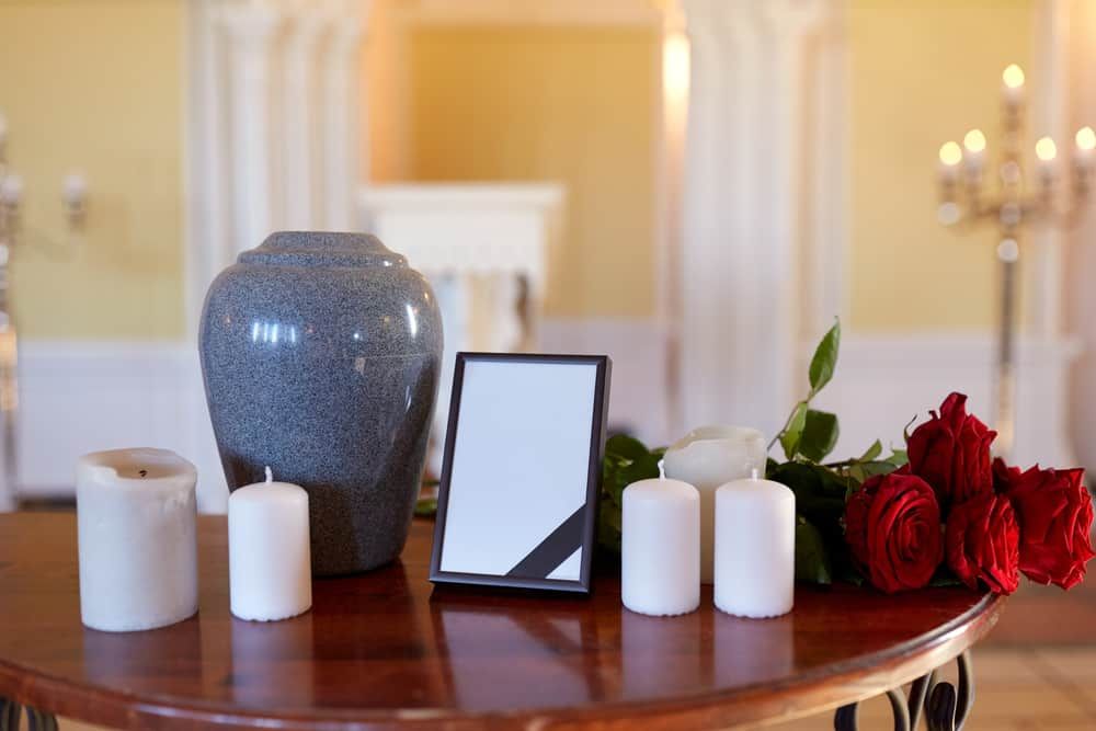 A table with a vase , candles , a picture frame and roses on it.