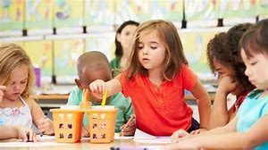 A group of children are sitting at a table in a classroom.