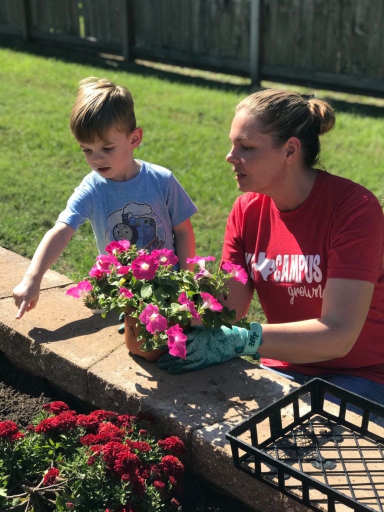 A woman and a child are planting flowers in a garden.