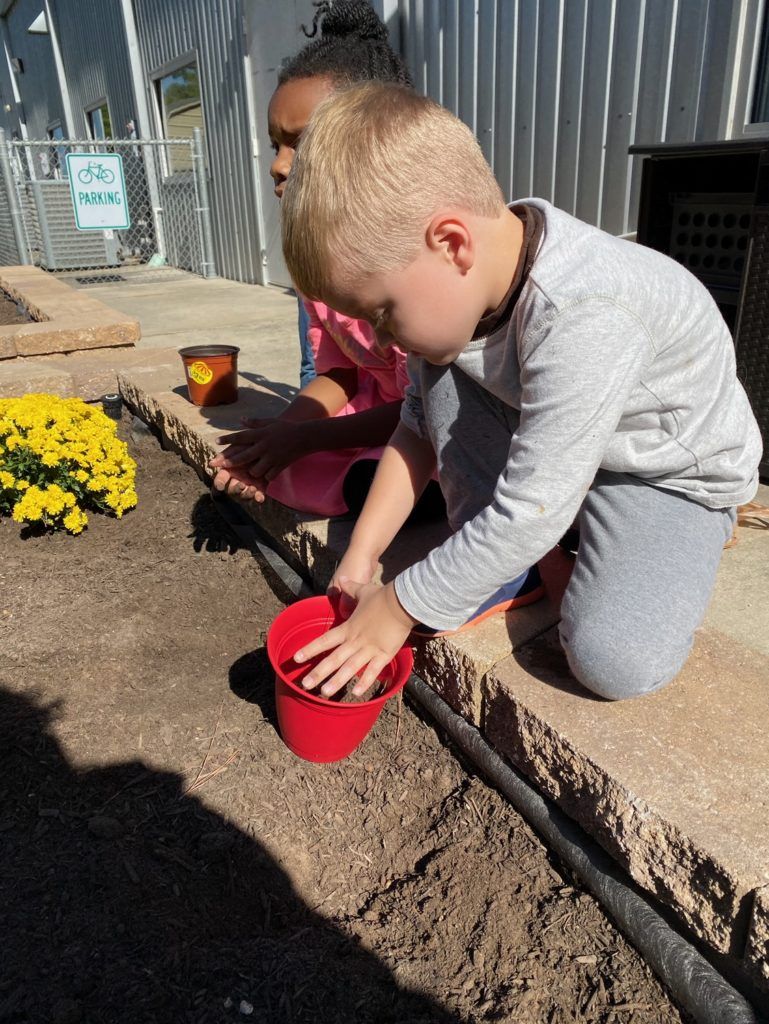 A boy and a girl are planting flowers in a garden.