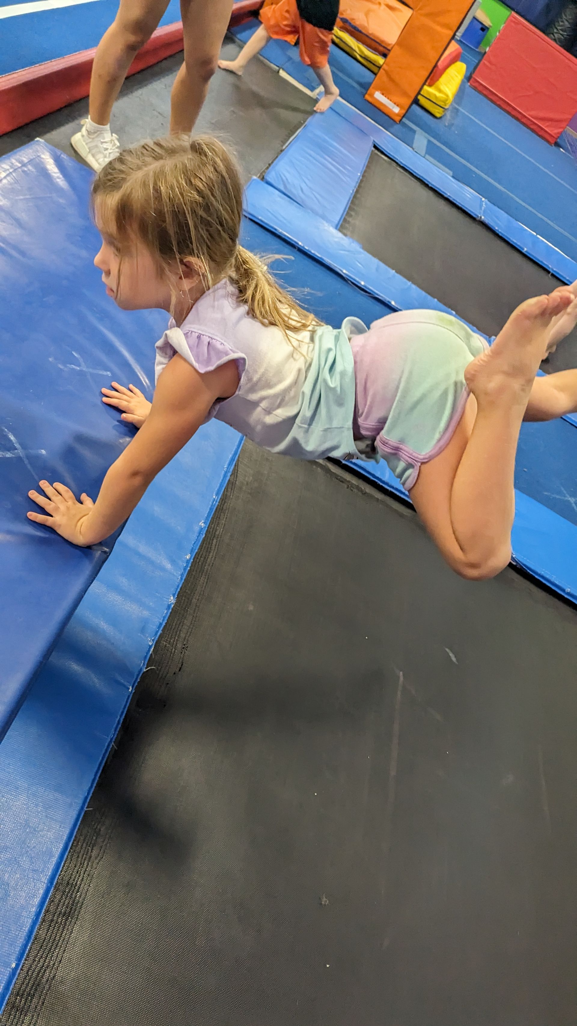 A little girl is doing a handstand on a trampoline.