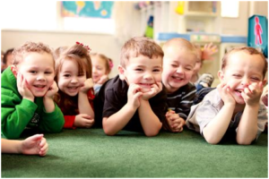 A group of children are laying on the floor and smiling