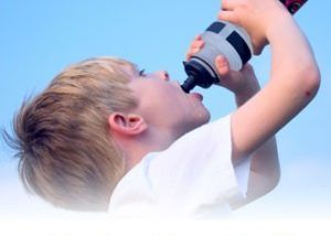 A young boy is drinking water from a bottle