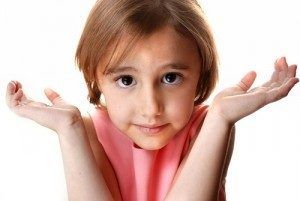 A little girl in a pink dress is shrugging her shoulders.