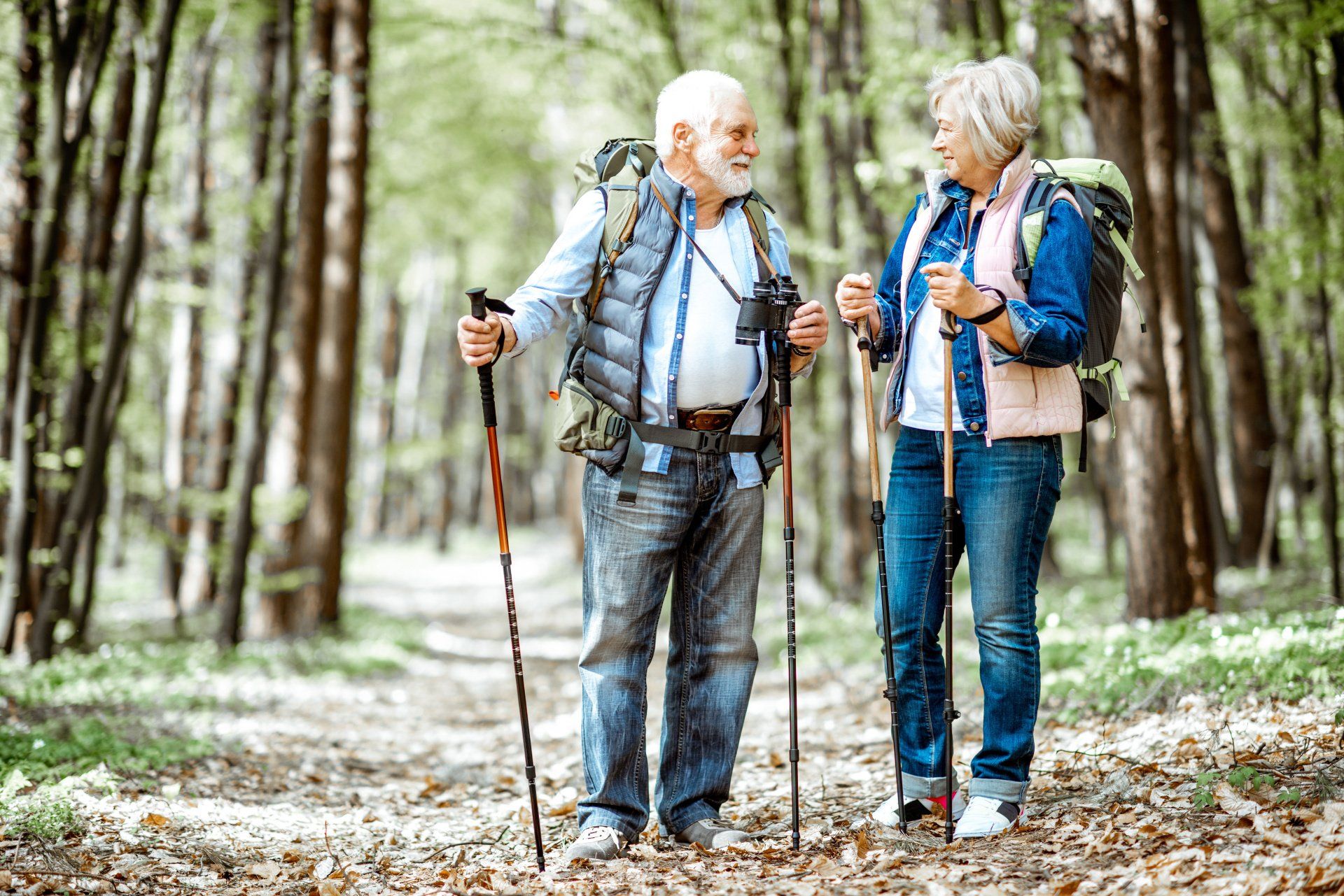 A man and a woman are hiking in the woods.