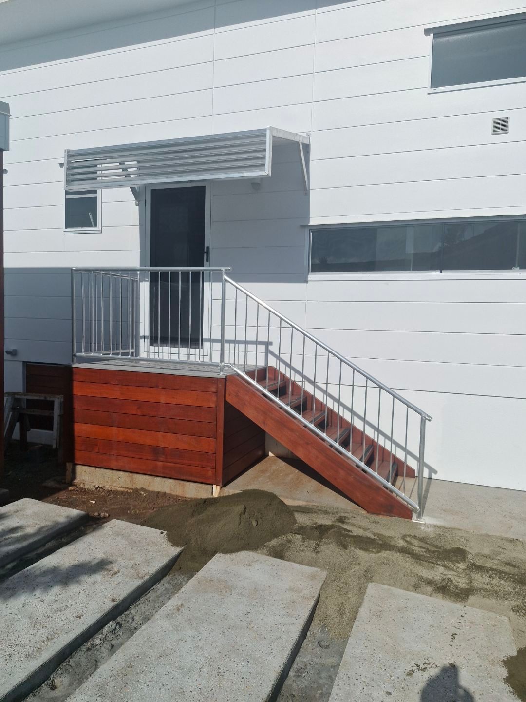 Exterior view of a wooden deck with stairs leading up to a white building entrance — Metaltrendz in Kunda Park, QLD