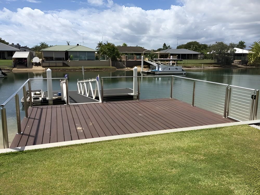 A Wooden Deck Overlooking a Body of Water With Houses in the Background — Metaltrendz in Kunda Park, QLD