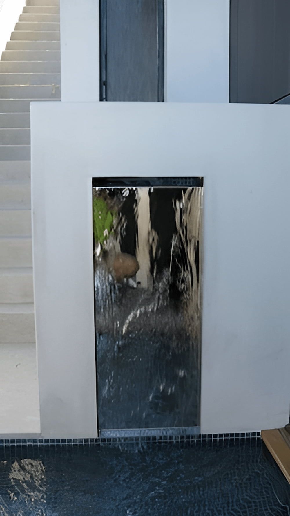 Water flows down a dark metallic panel set into a white wall, with a pool below — Metaltrendz in Kunda Park, QLD