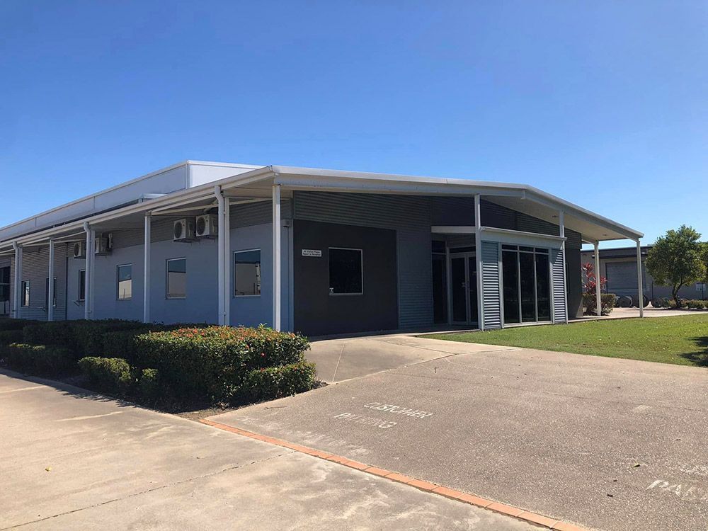 A Large Building With a Lot of Windows is Sitting on Top of a Lush Green Field — Schmucker Cleaning in Gulliver, QLD