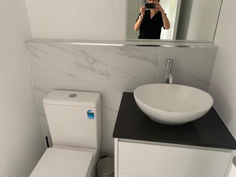 A White Toilet Next to A Black Vanity with A White Bowl Sink — Schmucker Cleaning In Gulliver, QLD