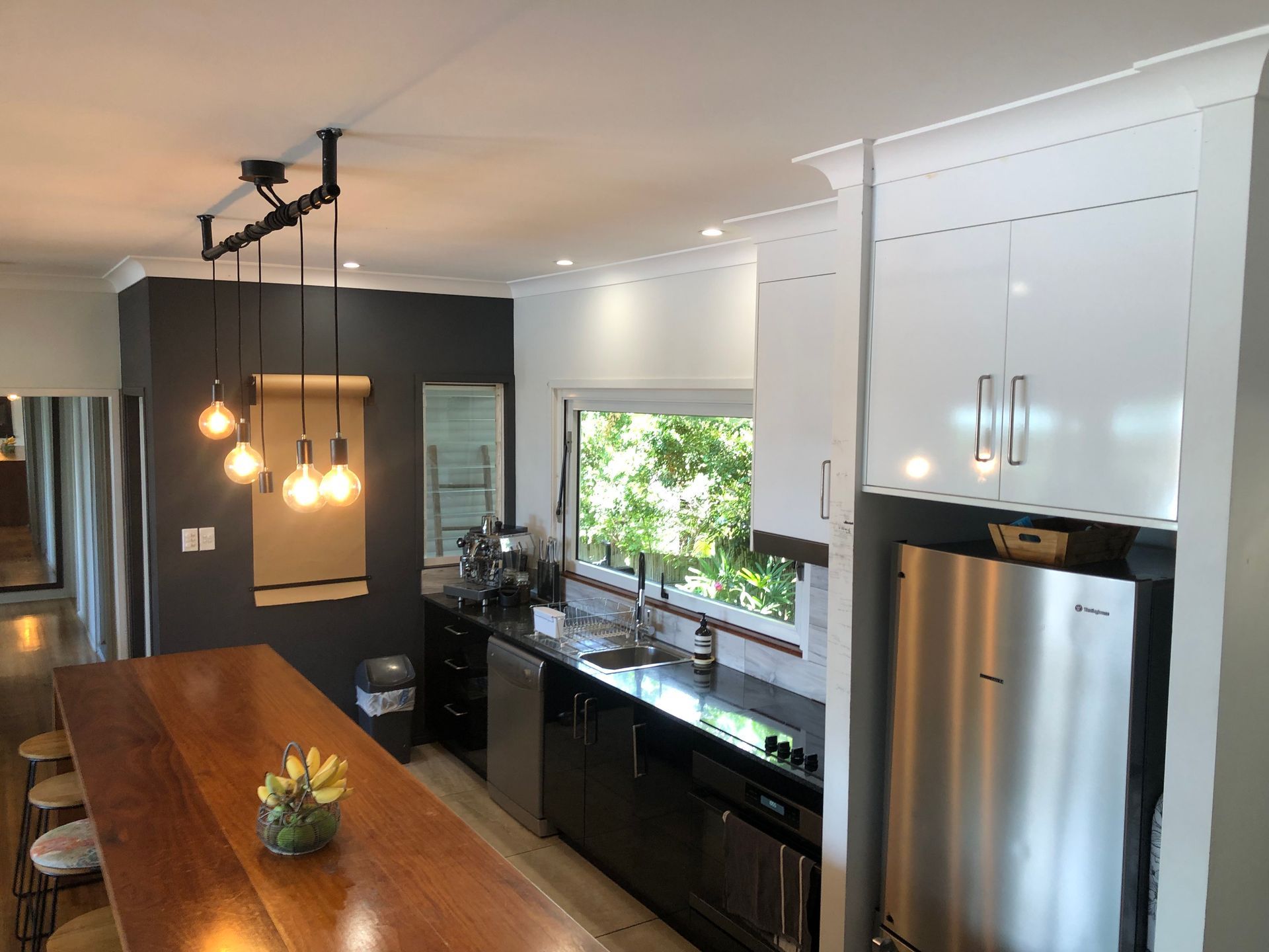 A Clean Kitchen With An Island And Bar Stools A Fridge And A Sink And A Window — Schmucker Cleaning in Gulliver, QLD