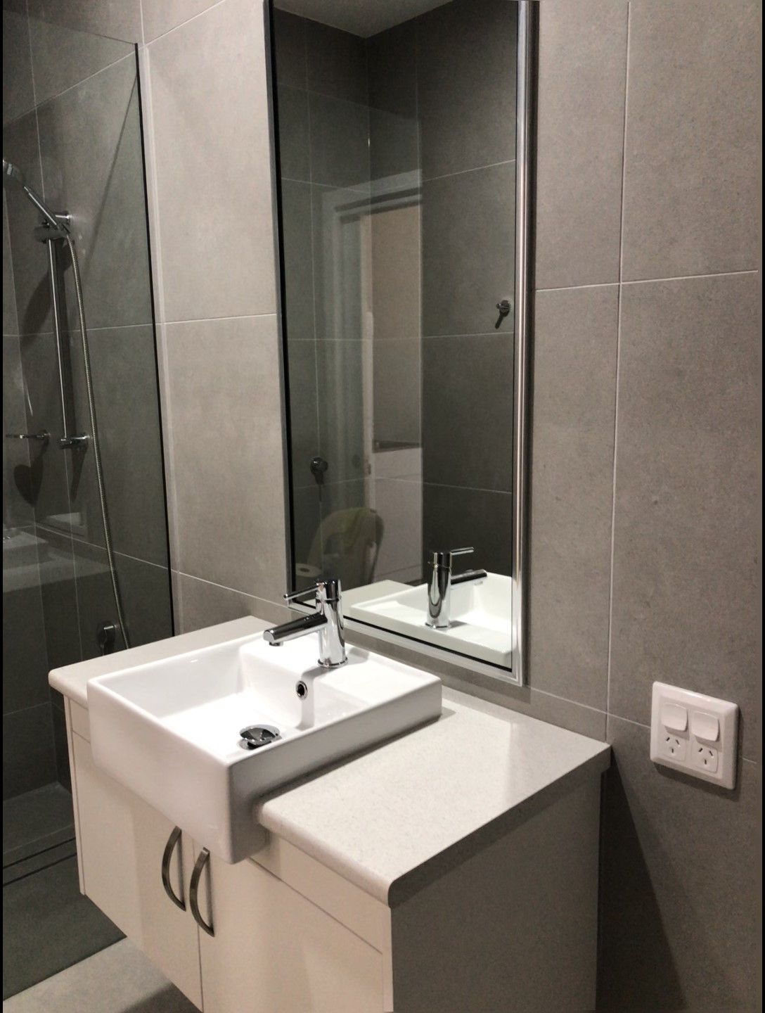 A bathroom basin with mirror on the wall and shower in the background — Schmucker Cleaning in Gulliver, QLD