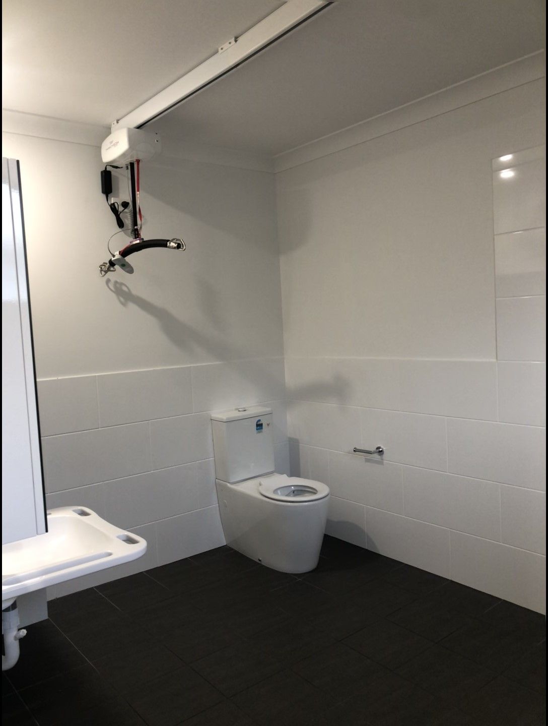 A Large Bathroom with a toilet and equipment set up on the ceiling for NDIS purposes — Schmucker Cleaning in Gulliver, QLD