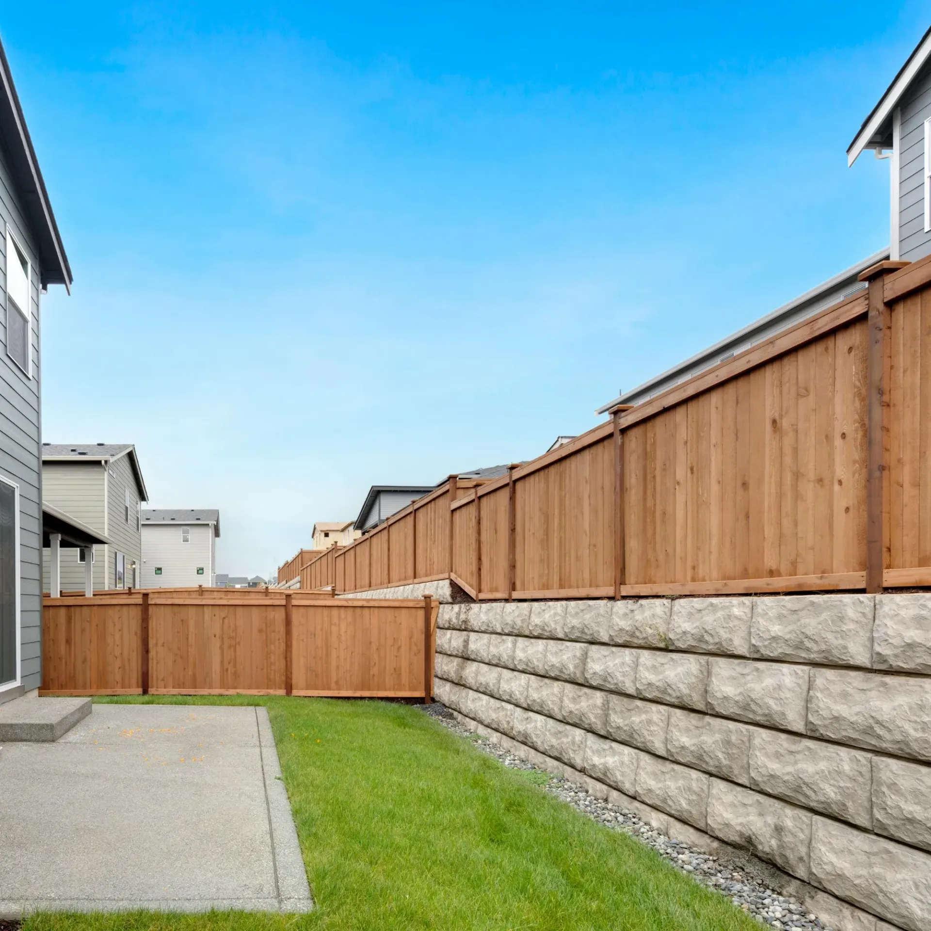 Boots & Boards Fencing - A backyard with a wooden fence and a stone wall.