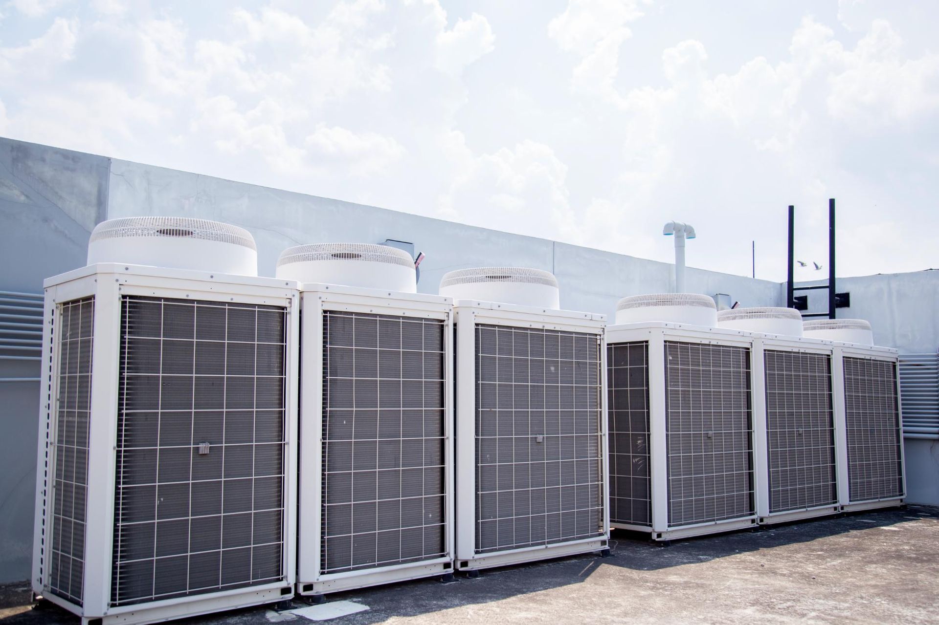 Air conditioning units on a building rooftop against a blue sky.