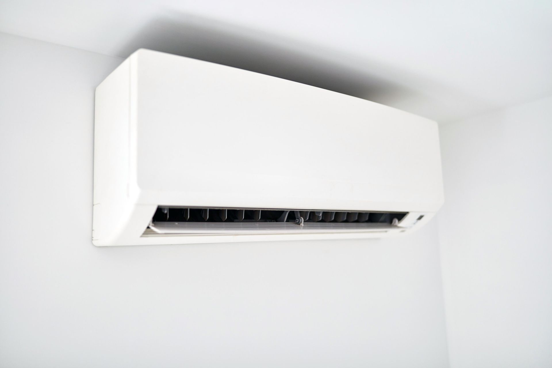 White wall-mounted air conditioning unit on a white wall.