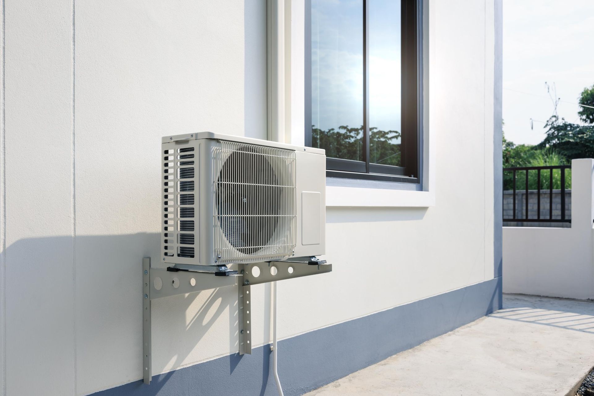 Air conditioning unit mounted on a white wall near a window.