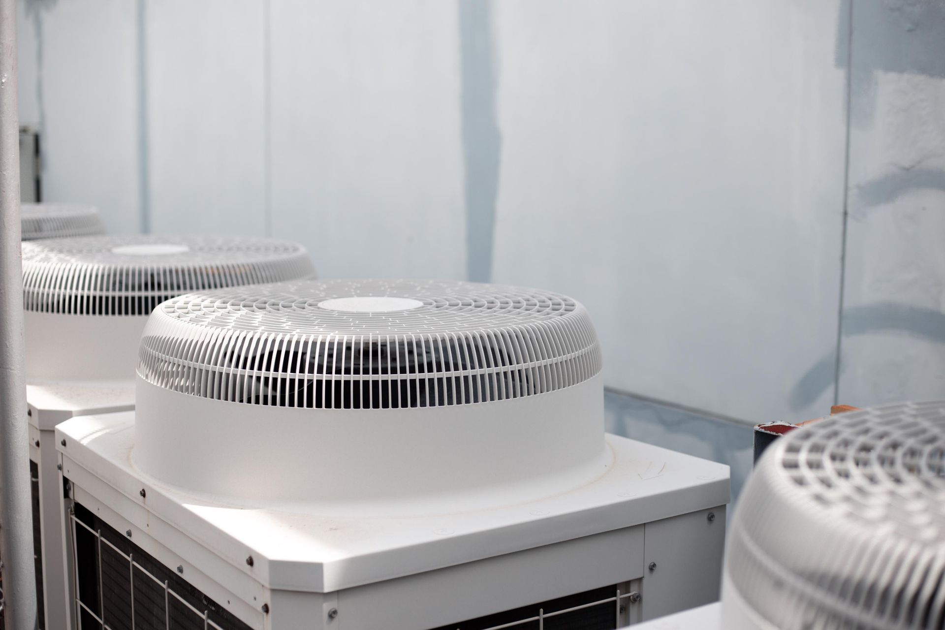 White air conditioning units with fan covers, in a row.