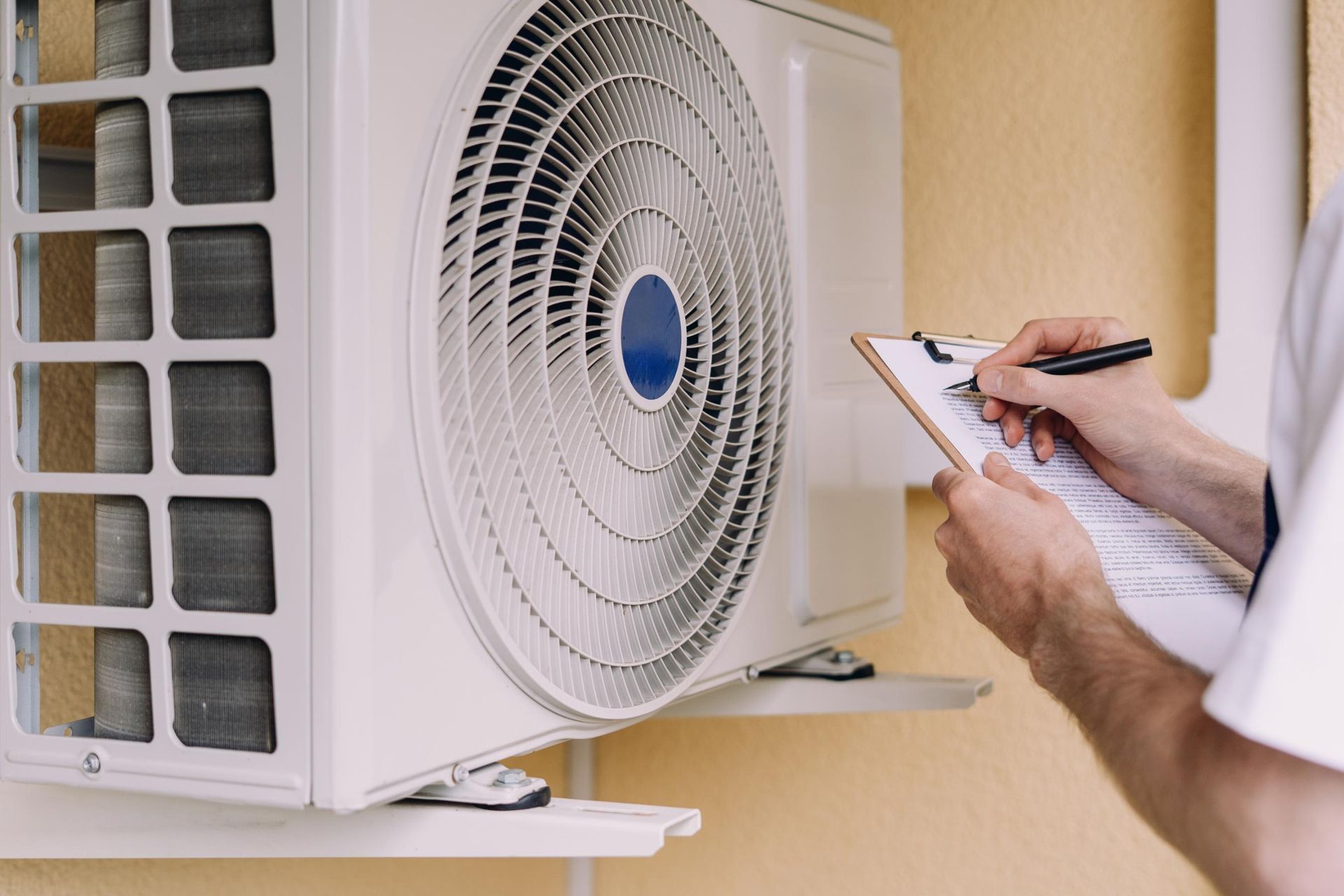 HVAC technician inspecting an outdoor air conditioning unit, taking notes on a clipboard.