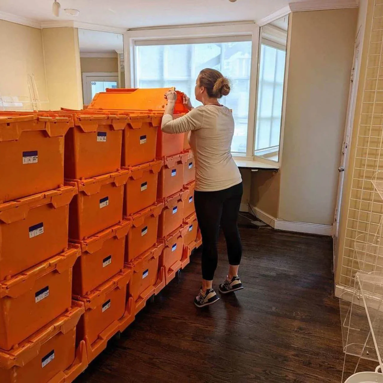 A woman is standing in front of a stack of orange boxes.