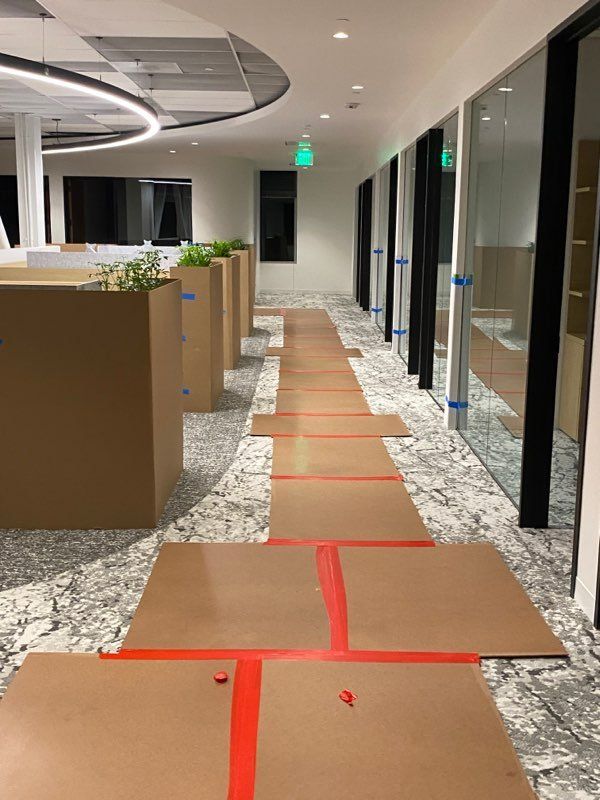 A hallway in an office building with cardboard boxes on the floor.