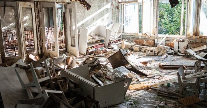 A room in an abandoned building with a lot of trash on the floor.