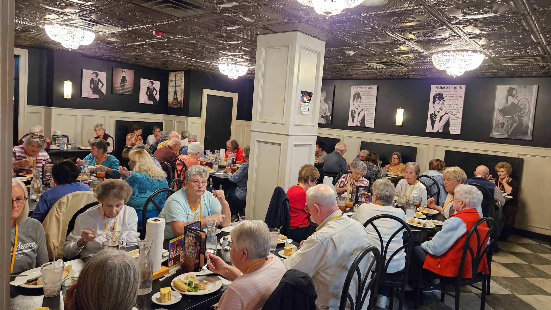 A large group of people are sitting at tables in a restaurant eating food.