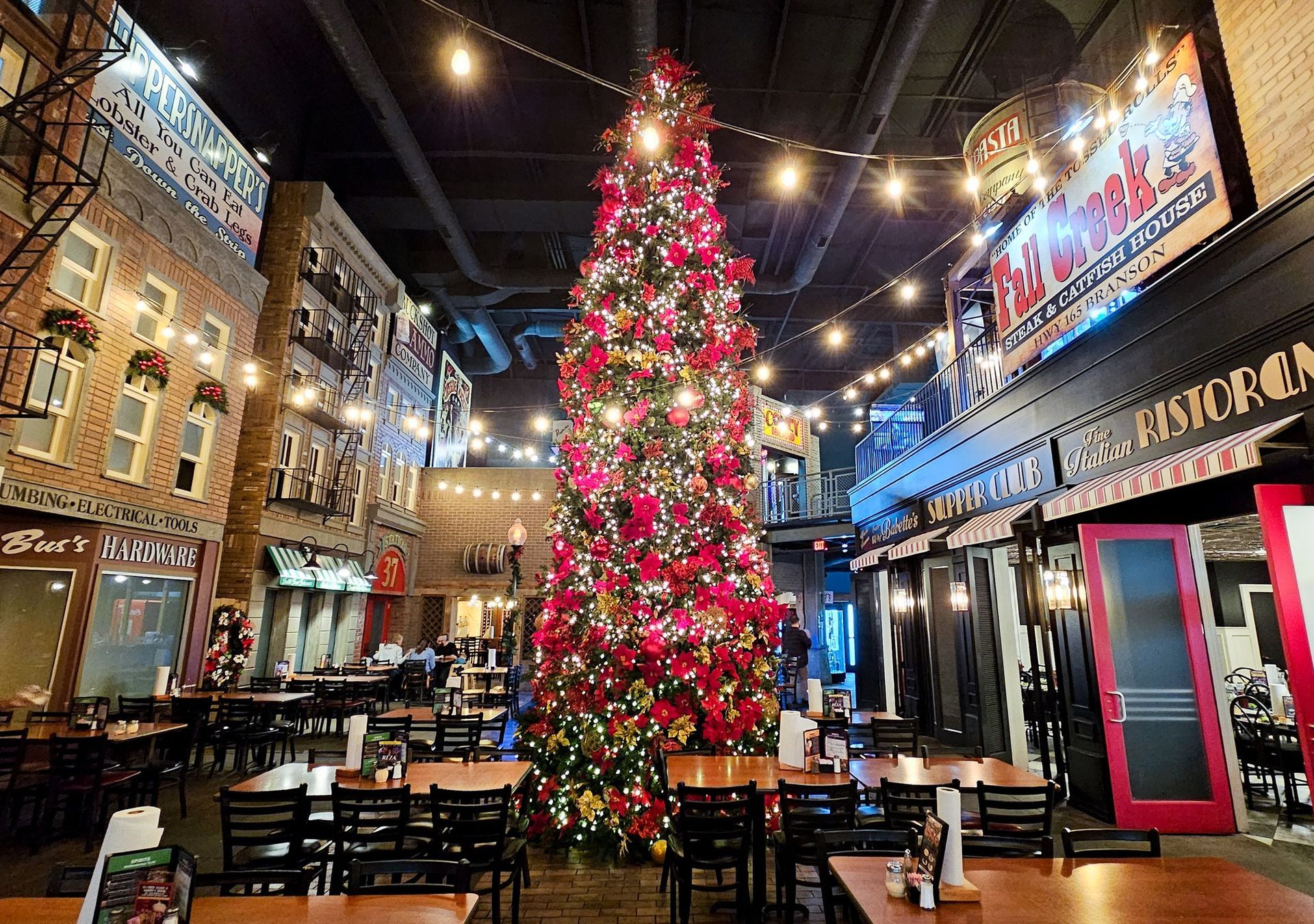 A large christmas tree is in the middle of a restaurant.