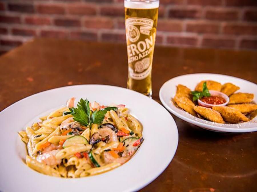 Two plates of food and a glass of beer on a table.