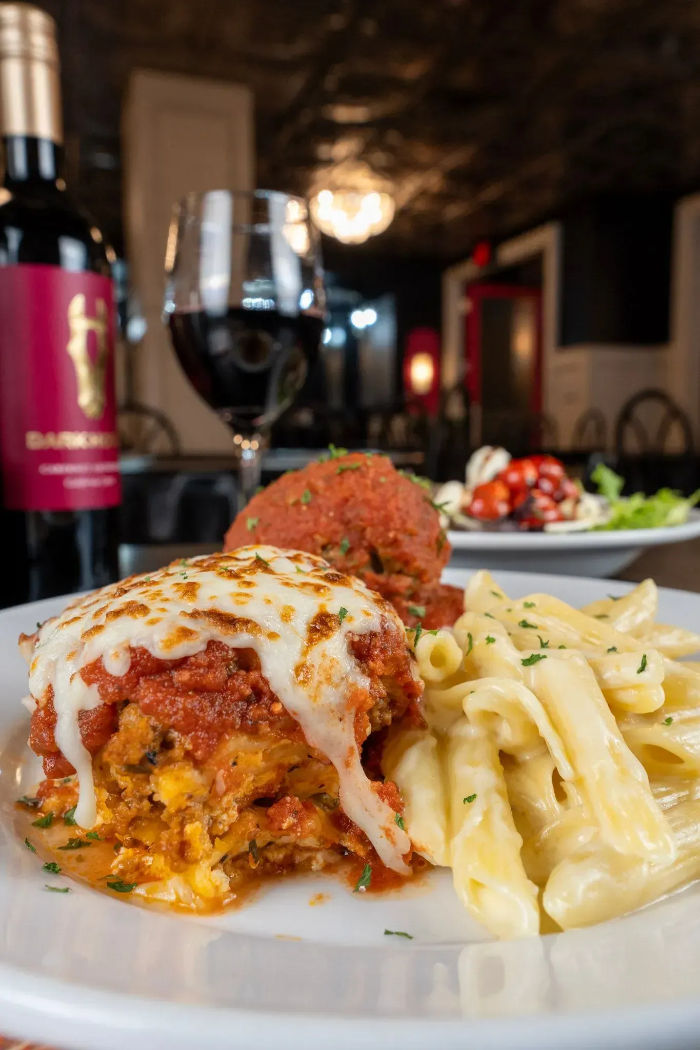 A plate of food with a bottle of wine in the background.