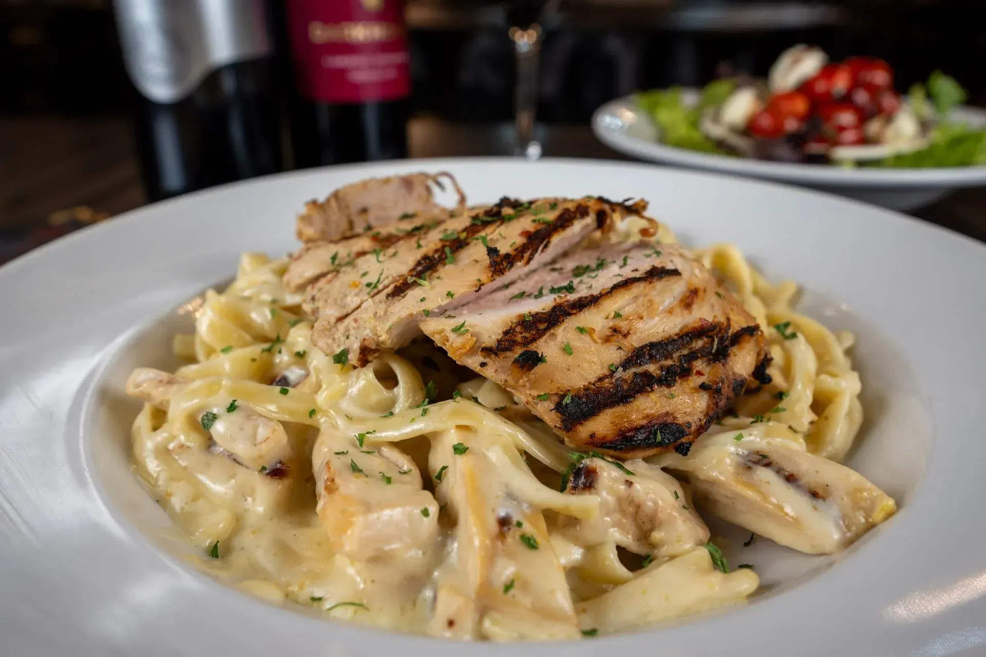 A plate of pasta with chicken and mushrooms on a table.
