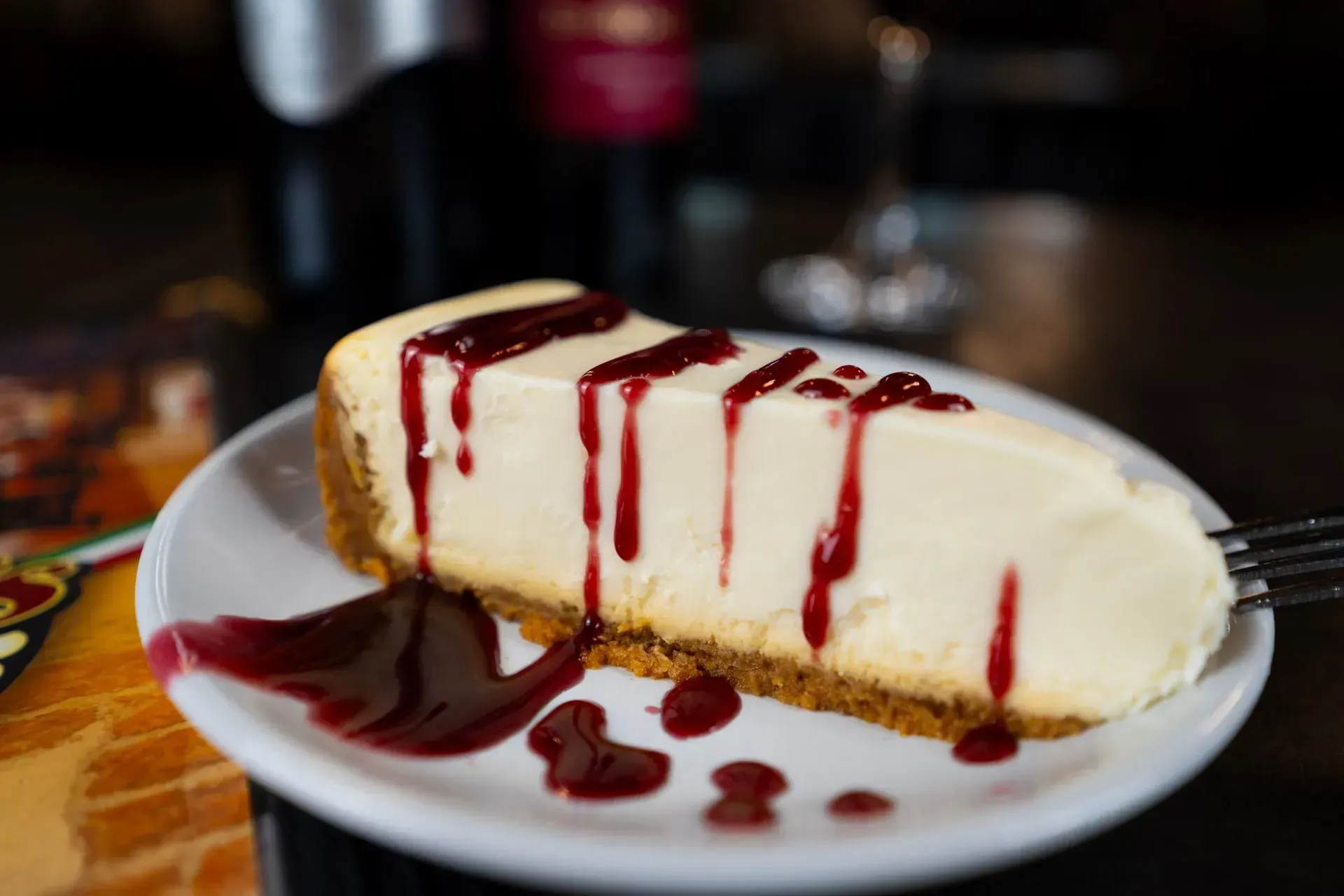 A slice of cheesecake with raspberry sauce on a white plate.