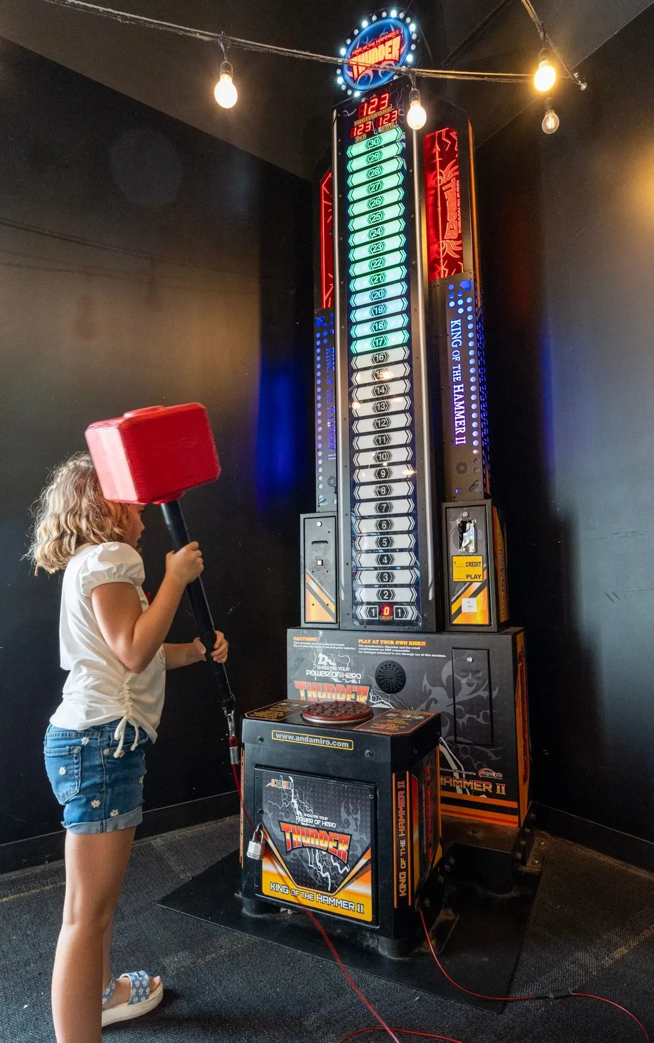 A young girl is playing a video game with a hammer on her head.