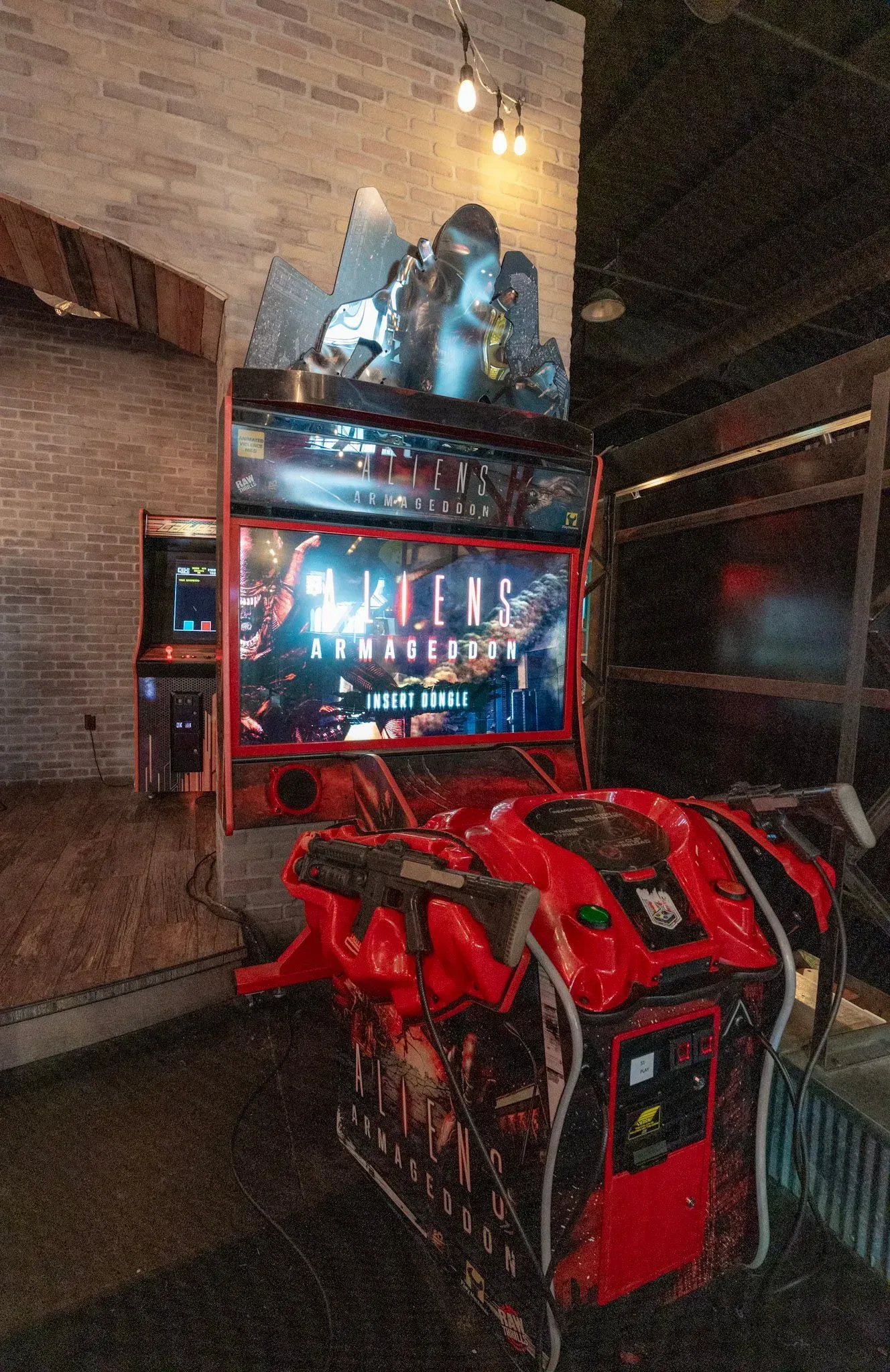 A red arcade machine is sitting in a dark room.