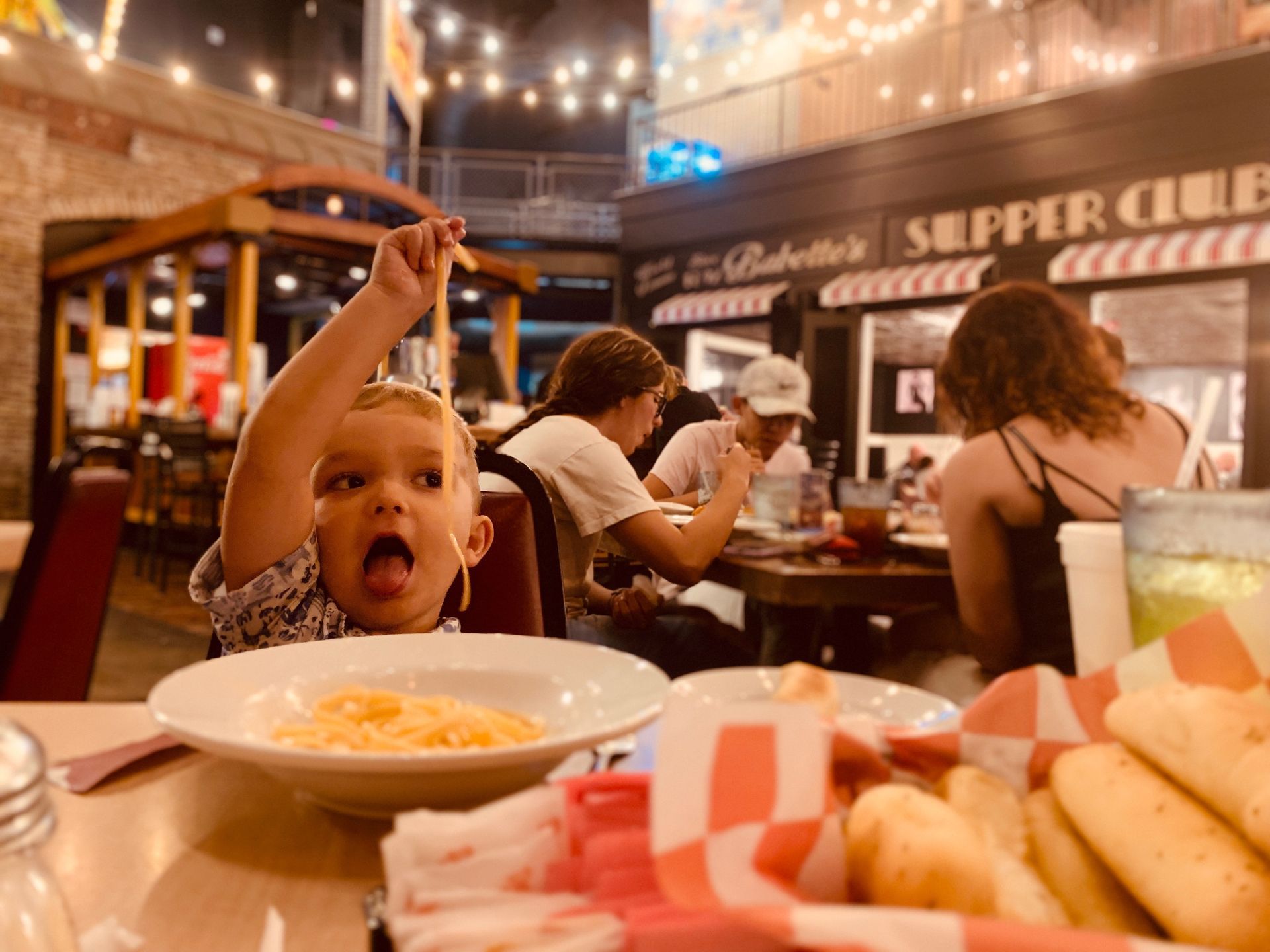 A little girl is sitting at a table with a bowl of food.