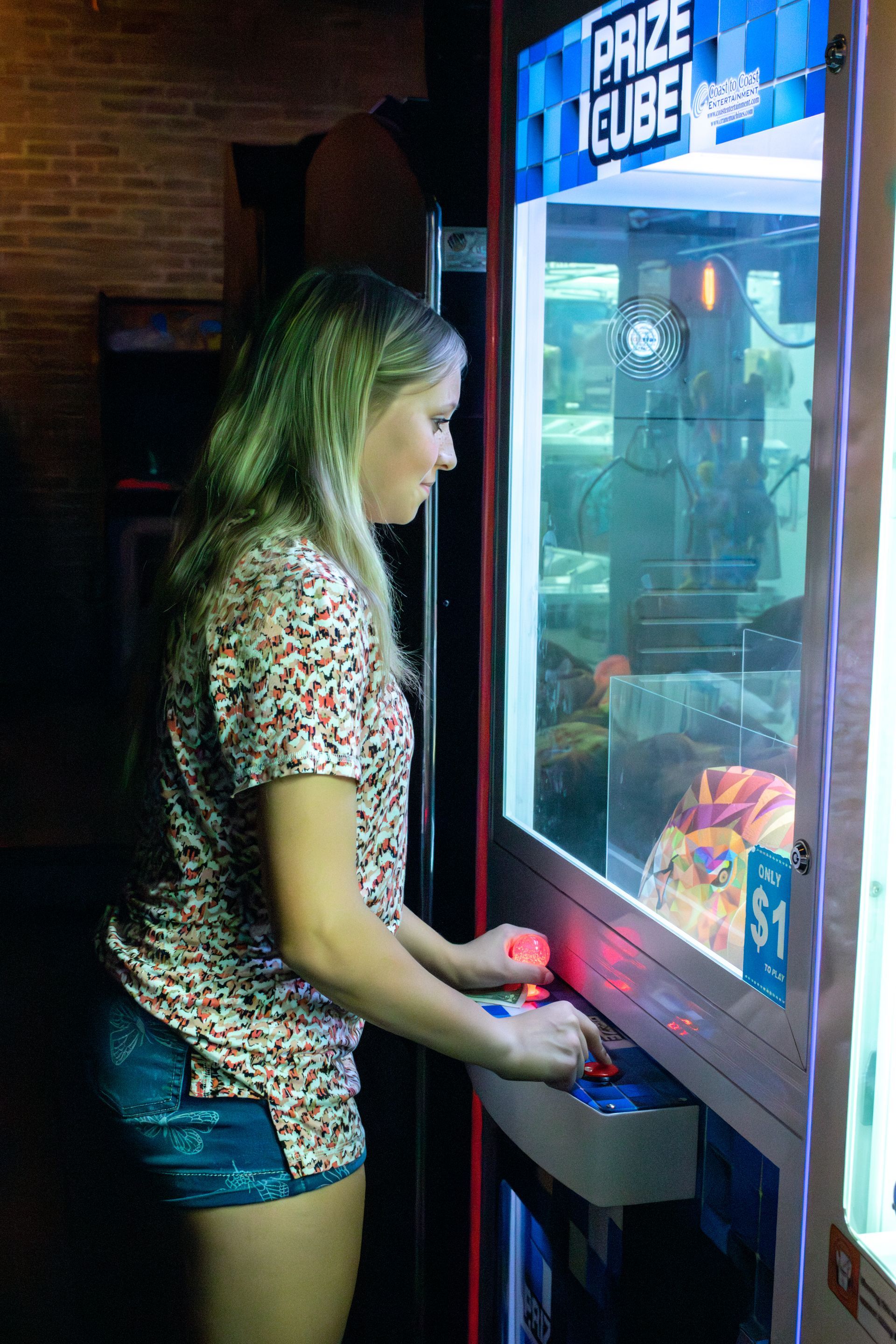 A woman is playing a prize cube game in an arcade.